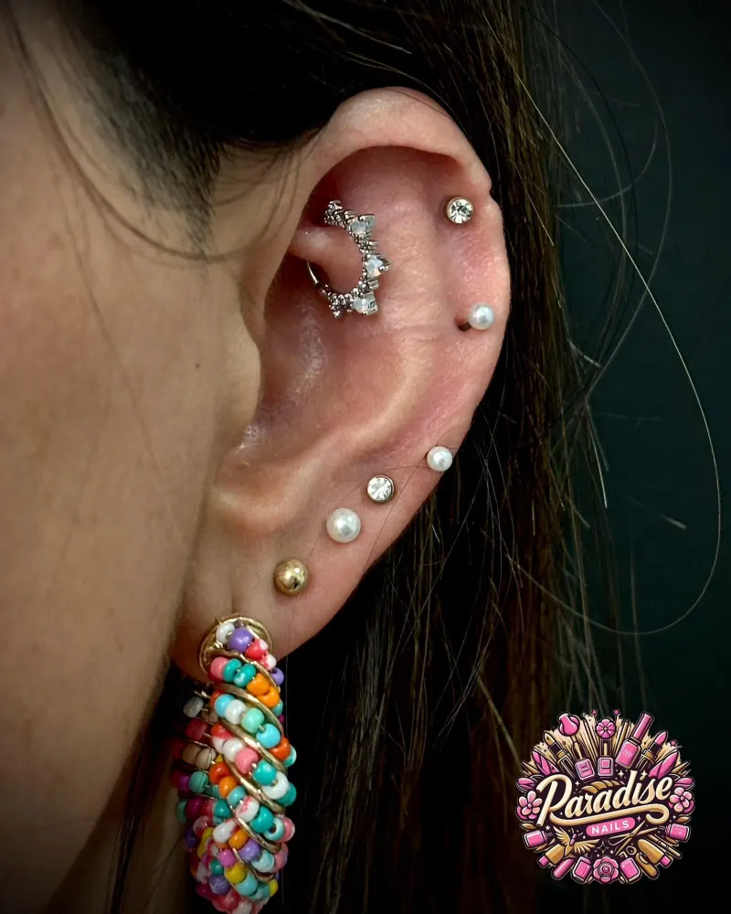 Composición de piercings en la oreja con joyas de circonita