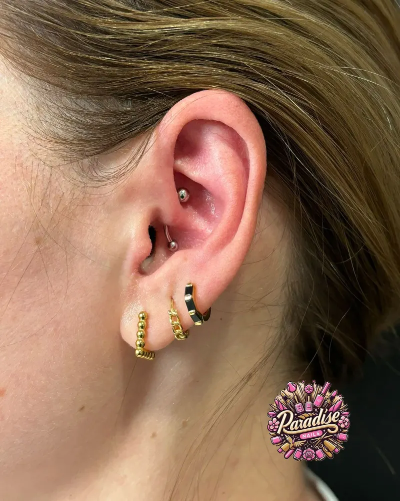 Composición de piercings en la oreja con aros dorados