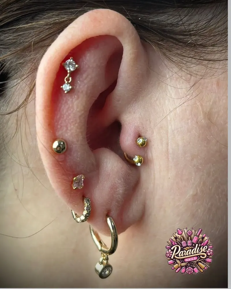 Composición de piercings en la oreja con joyas doradas, hecha en Sevilla