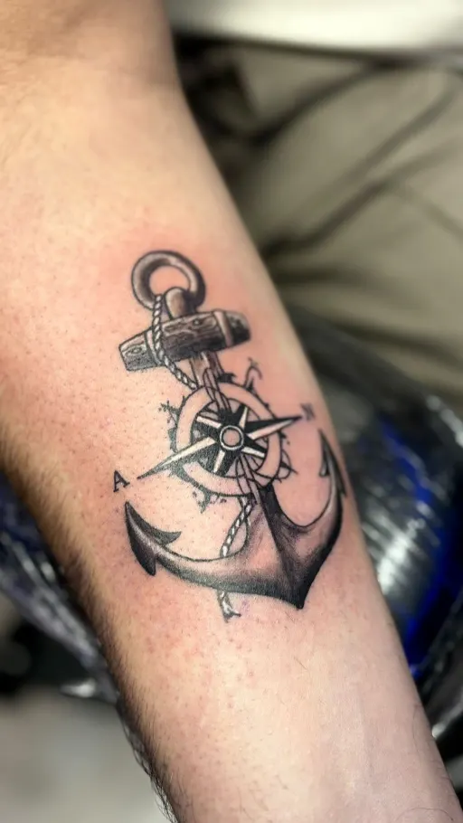 Tatuaje black & grey de un ancla con timón en el antebrazo
