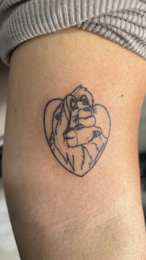 Tatuaje fine line de un corazón con una escena de cuento en el brazo