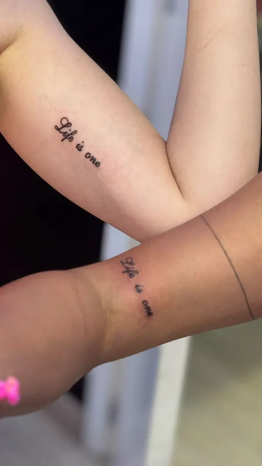 Tatuajes de pareja a juego con una frase en fine line en el antebrazo